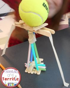 a tennis ball is on top of some sticks with pencils in front of it