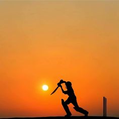 the silhouette of a person holding a baseball bat in front of an orange sky at sunset