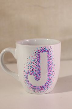 a white coffee cup with colorful sprinkles and the letter j on it