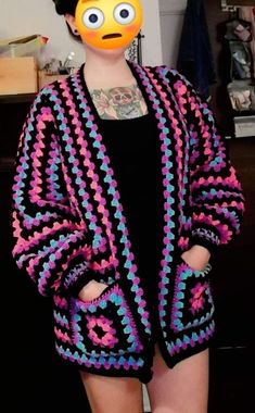 a woman with an emoticive face painted on her face wearing a crochet jacket