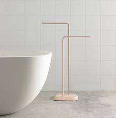 a white bath tub sitting next to a wooden stand in front of a white tiled wall