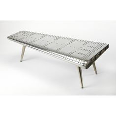 a metal bench sitting on top of a white floor covered in riveted dots