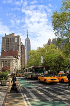 people crossing the street in new york city with yellow cabs and buses on it