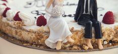 a wedding cake with figurines on top of it and berries around the edge