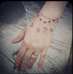 a person's hand with a tattoo on it and some beads hanging from the wrist