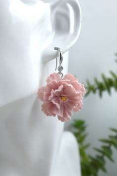 a pair of earrings with pink flowers hanging from it's earwires on a white mannequin