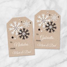 two tags with snowflakes on them sitting on top of a white marble surface