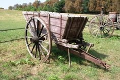 an old wooden wagon sitting on top of a grass covered field