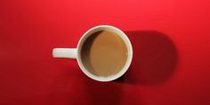 a cup of coffee sitting on top of a red wall