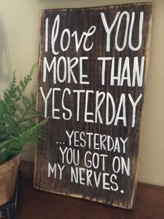 a wooden sign that says i love you more than yesterday, and next to a potted plant