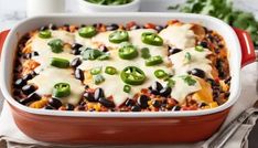 a red casserole dish filled with black beans, cheese and green peppers