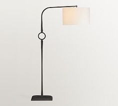 a black floor lamp with a white shade on the base and a round light fixture