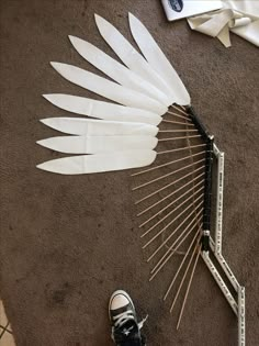 a pair of shoes is sitting on the floor next to a feather fan and measuring tape