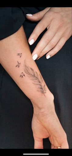 a woman's arm with a feather and stars tattoo on her left hand,