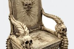 a skeleton chair with two skulls on it's back and arms, sitting in front of a white background