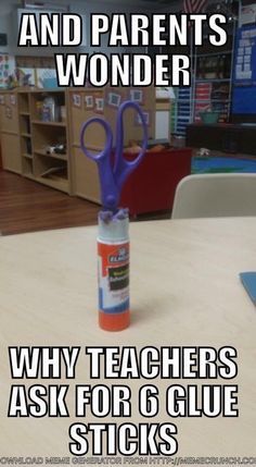 a blue pair of scissors sitting on top of a table next to an orange tube