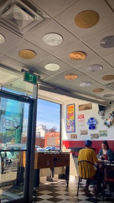 two people sitting at a table in front of a window with lots of lights on it