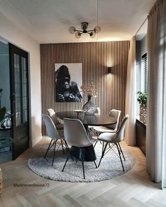 a dining room table with chairs and a painting on the wall in the back ground