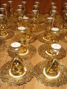 a table topped with lots of gold colored glass candlesticks next to each other