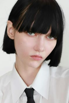 a woman with black hair and bangs wearing a white shirt, tie and dress shirt