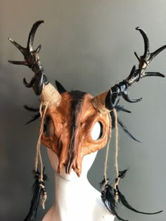 an animal's head with horns and feathers on top of a white mannequin