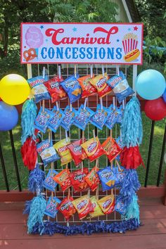 a candy bar with balloons and streamers on the fence for an outdoor carnival concesions display