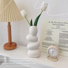 there is a clock and some flowers on the table next to a book with instructions