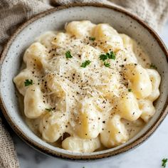 a bowl filled with macaroni and cheese covered in parmesan sprinkles