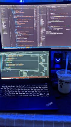 a laptop computer sitting on top of a desk next to a cup of coffee and monitor