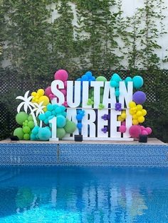 a sign that says suttan free next to a pool with balloons and palm trees