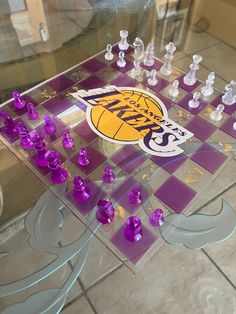 a glass table with purple chess pieces on it and the lakers logo painted on top