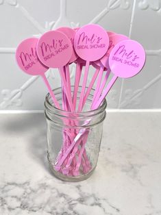 there are pink paper straws in a mason jar with name tags on the top