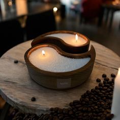 two tea lights sitting on top of a wooden table next to coffee beans and candles