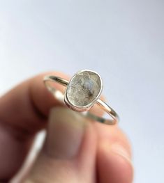 a close up of a person holding a ring with a stone in it's middle