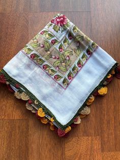 the table cloth is laying on top of the wooden floor with pomegranates around it