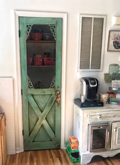 a kitchen with a green door and wooden floors