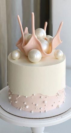 a white cake with pink icing and pearls on top