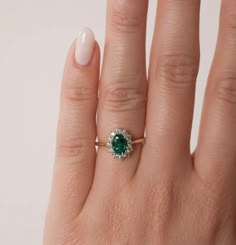 a woman's hand with a ring on it and a green stone in the middle