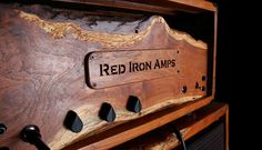 the red iron amps logo is engraved on an old wooden cabinet with black knobs