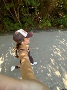 a person taking a selfie in the middle of a road with trees and bushes behind them