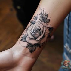 a black and white rose tattoo on the left wrist, with leaves around it's edges