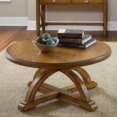 a wooden table topped with books and a bowl of fruit next to a pile of books