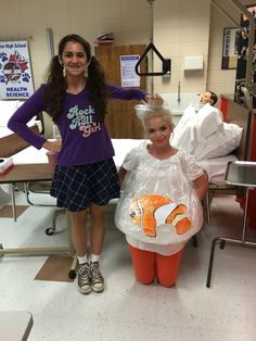 two girls standing next to each other in a room with plastic bags on the floor