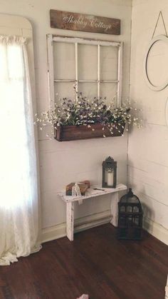 a white bench with flowers in a window box on the wall next to a birdcage