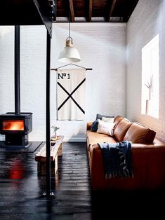 a living room with a brown leather couch and wood burning stove