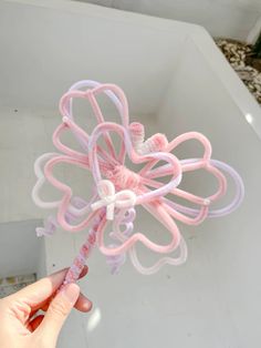 a hand holding a pink and white flower shaped object