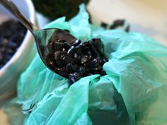 a spoon full of black beans sitting on top of a green bag