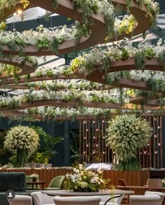 the inside of a restaurant with tables, chairs and plants hanging from the rafters