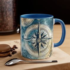 a blue coffee mug sitting on top of a wooden cutting board next to a spoon