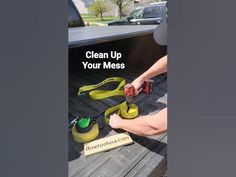 a man is cleaning the back of a truck with a yellow hose and two green sprayers